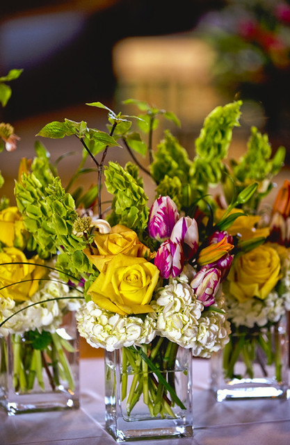 This is a colorful wedding centerpiece made of yellow roses and green bells