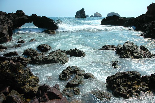 Wave crashing in under the little arch, black rocks, blue water, islets, Pacific Ocean, South Matzatlan, Sinaloa, Mexico by Wonderlane