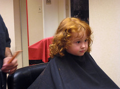 Speck with red curls and serious expression, in haircut apron