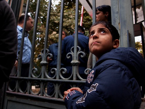 Seeing refugee families approach Greek riot police close gates to ministry building