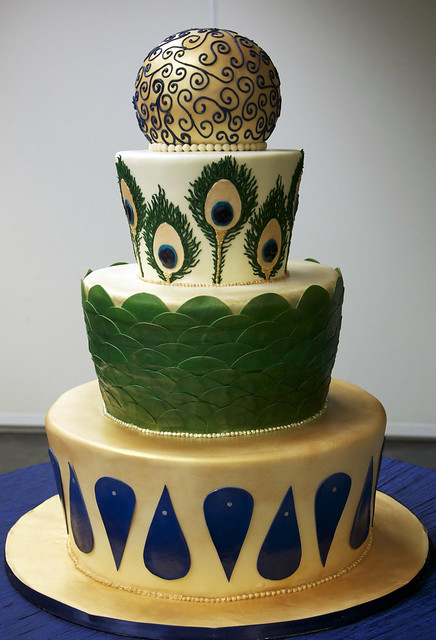 A large 3 tier peacock theme wedding cake in gold emerald green ivory and 