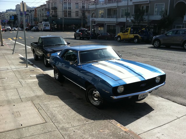 a 1960's era chevolet camaro parked on divisadero street at the intersection