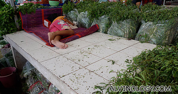 A child resting at a vegetable stall