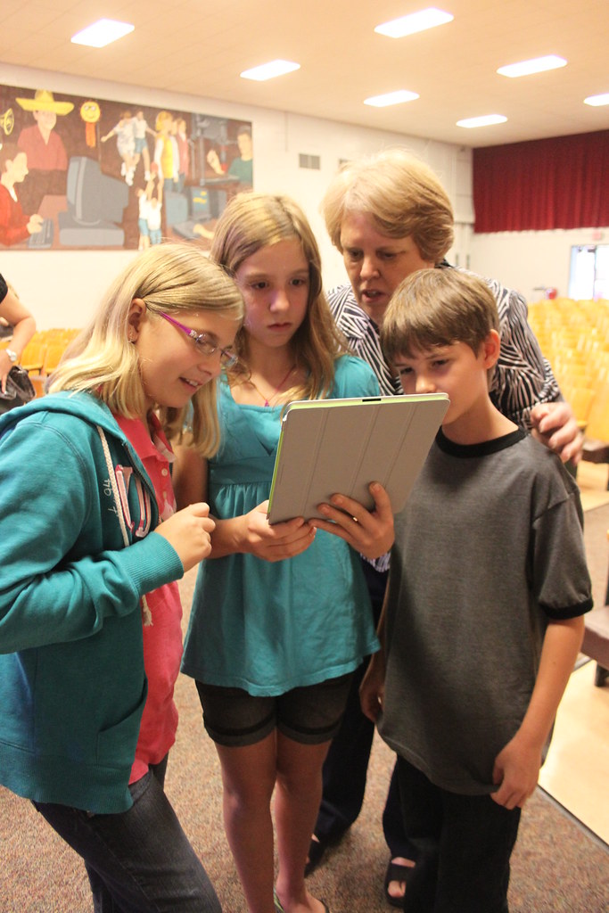 students gather around their teacher's ipad
