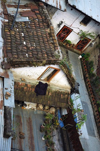 Rooftop porches of local abodes, potted plants, aluminum panels, tile roof, doors, windows, fabrics, Boudha, Kathmandu, Nepal by Wonderlane