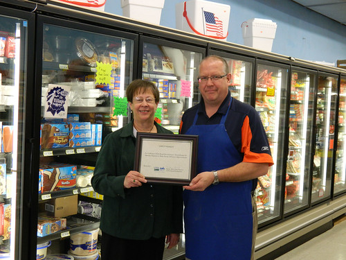Greg Yound of Greg’s Market in Exeter accepts certificate from State Director Maxine Moul for the new freezers resulting from an energy efficiency grant.