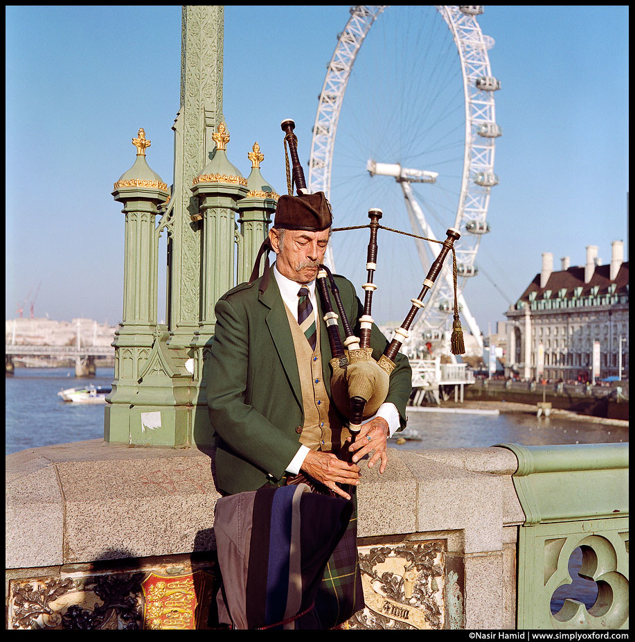 A man playing bagpipes, London