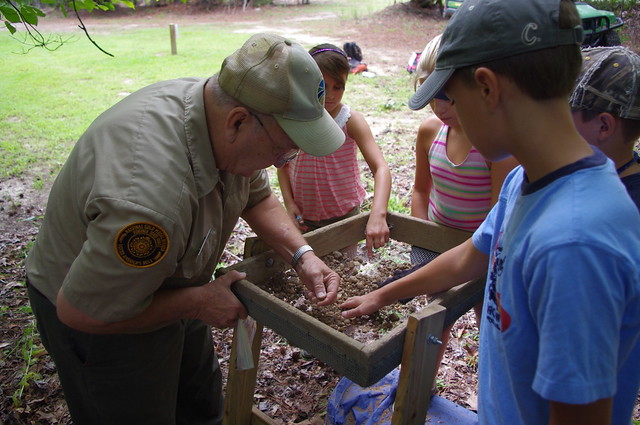 Jerry Travers teaches children how to use the soil screen to search for clues to the past.