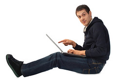Young man with laptop sits on floor
