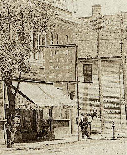 people usa signs man men history boys kids buildings walking advertising children awning clothing cafe mail indiana streetscene bicycles transportation drugs butler shops pedestrians cigars hotels storefronts businesses wagons barbers dekalbcounty realphoto hoosierrecollections