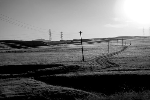 california road sunset blackandwhite bw grass silhouette landscape 50mm power sundown i5 hills dirt electricity poles ontheroad f28 sidewindow fromthecar drivebyshooting interstate5 notdriving shootingintothesun 80mphleavesnotimeforsecondshots