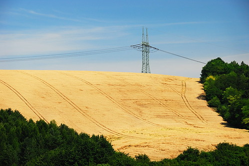 blue trees sky tractor green field lines landscape high european power grain tracks pole human presence voltage